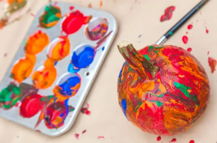 painting a small pumpkin with colorful paint
