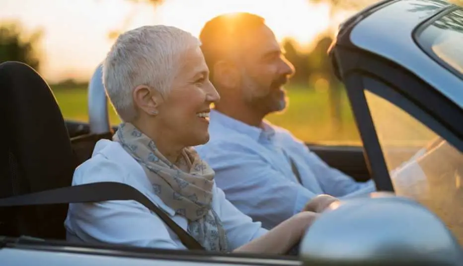 retired woman and man rding in a convertable