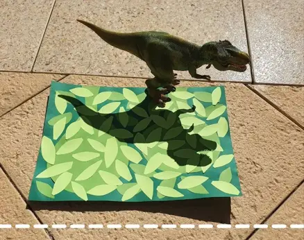 dinosaur set on paper outside to make a shadow which is traced on the paper
