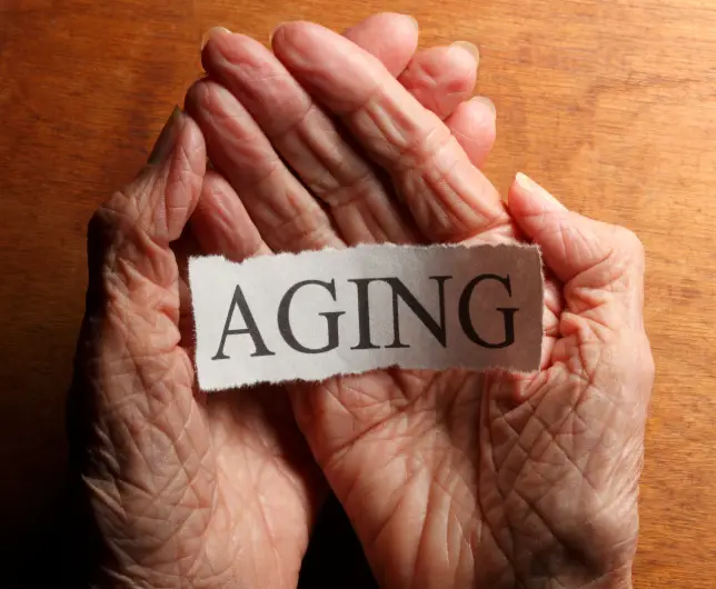 aging hands holding slip of paper with word aging