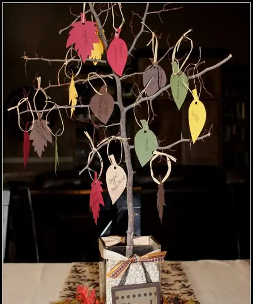 Tree branches in pot with colorful paper leaves