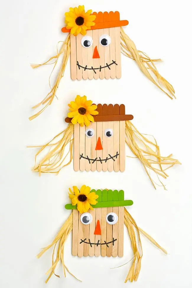 3 scarecrow oenaments made of craft sticks, googly eyes, raffia , felt and silk flowers
